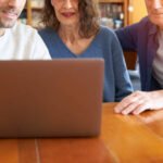 Male son teaching senior parents to  use laptop